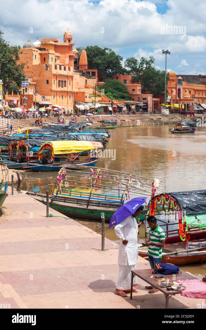 Chitrakoot, Madhya Pradesh, India : Two men stand by the colourful boats lining near the steps of Ramghat on the Mandakini river. Stock Photo