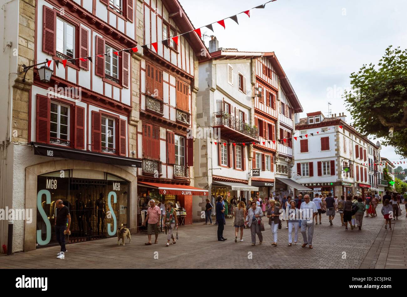Saint Jean de Luz, French Basque Country, France - July 13th, 2019 : People walk past traditional buildings in the historic center of Saint Jean de Lu Stock Photo