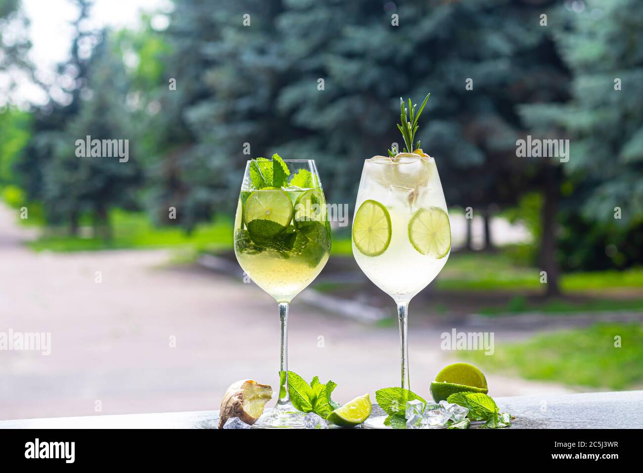 A refreshing summer cocktail with a slice of lime. Alcoholic drink. Garnished with a sprig of mint and ice cubes. In the bar. Foreground. Stock Photo