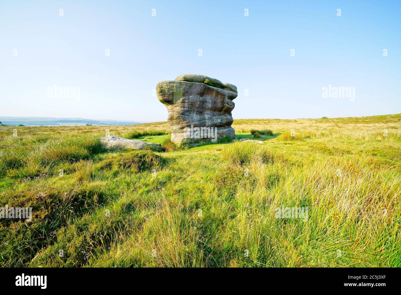 The Eagle Stone gritstone outcrop on Baslow Edge on a bright, hazy summer morning Stock Photo