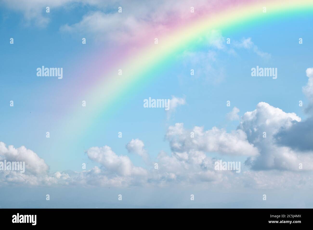Rainbow on blue sky with white cloud background. Stock Photo