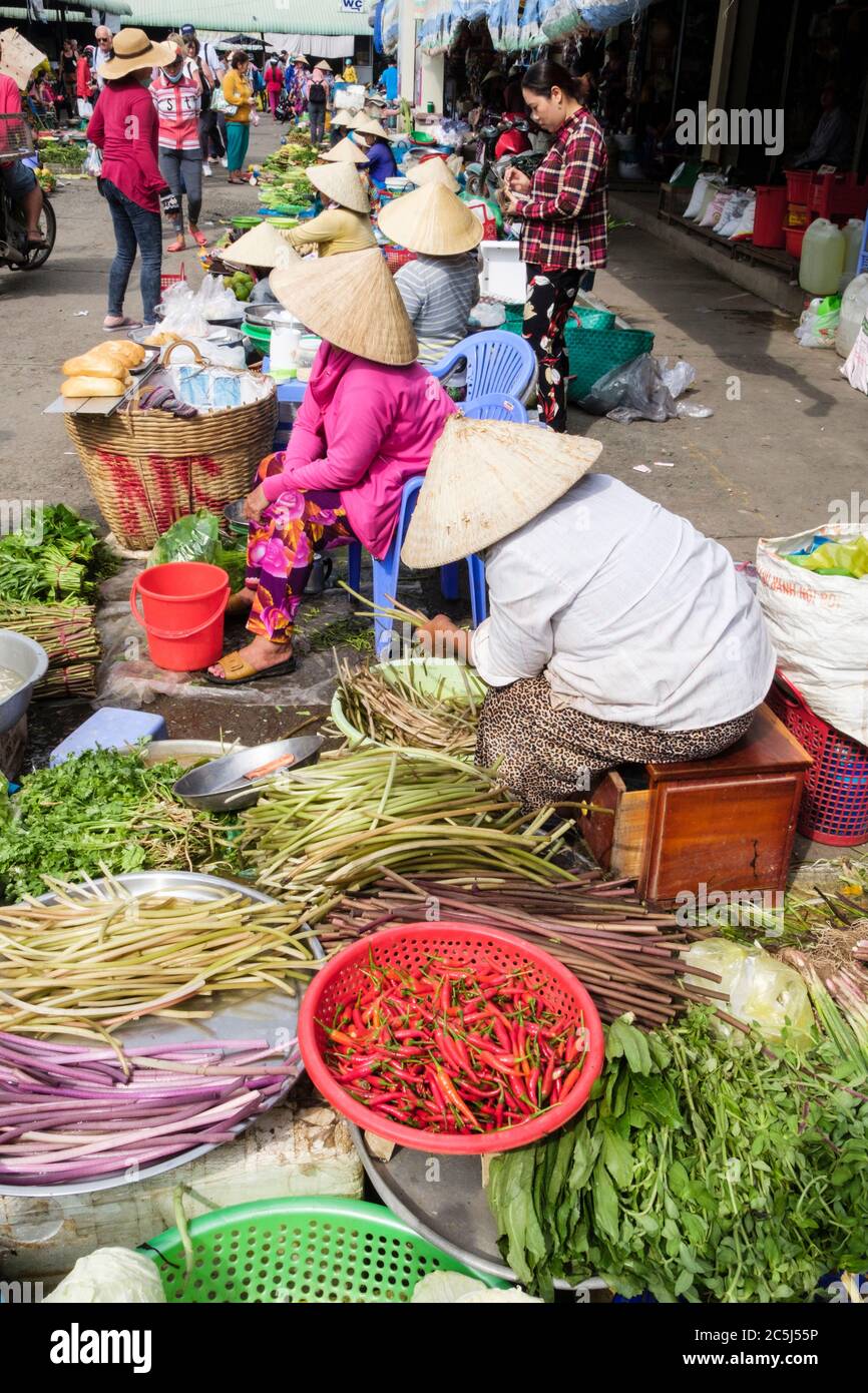 Vietnamese women stallholders wearing conical hats displaying fresh local fruit and vegetables for sale in a food market. Can Tho Mekong Delta Vietnam Stock Photo