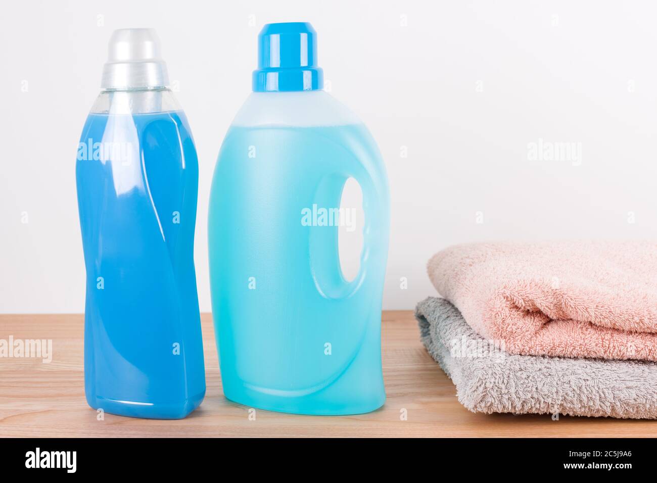Bottles of detergent and fabric softener with clean towels on wooden