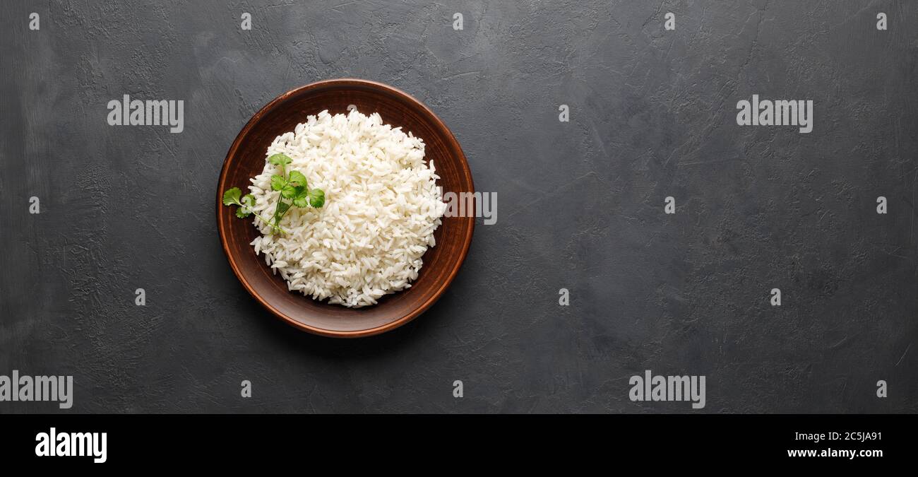 Boiled rice in a brown plate on black concrete background. Asian food ...