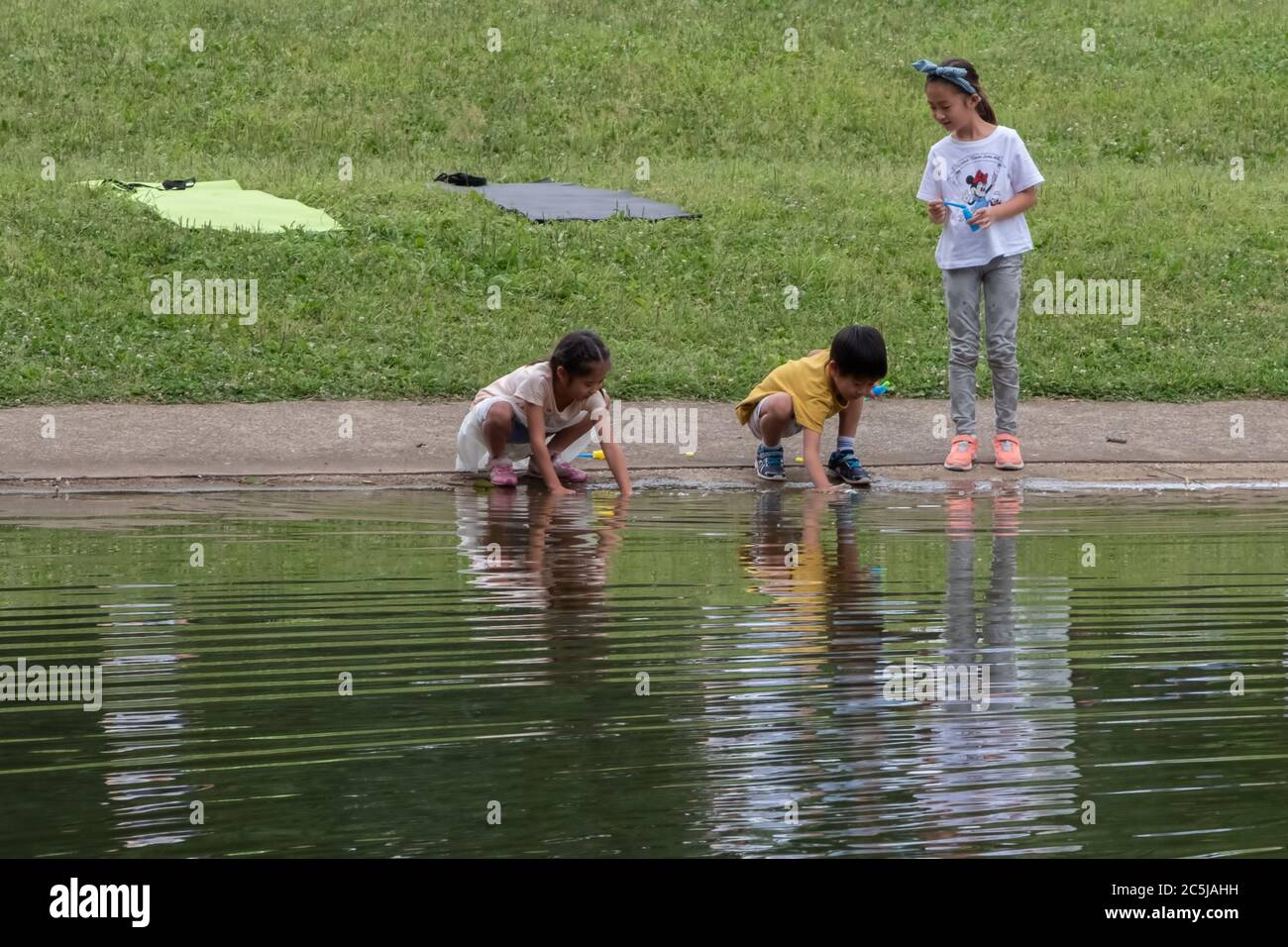 Children playing with water at a pond in Yoyogi Park, Tokyo, Japan Stock Photo