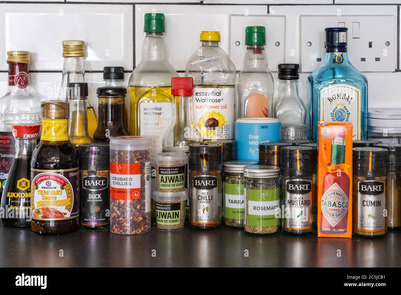 Upright household cooking condiments with oils, soy sauce, sauces and herbs and spices on a kitchen worktop in a UK house Stock Photo