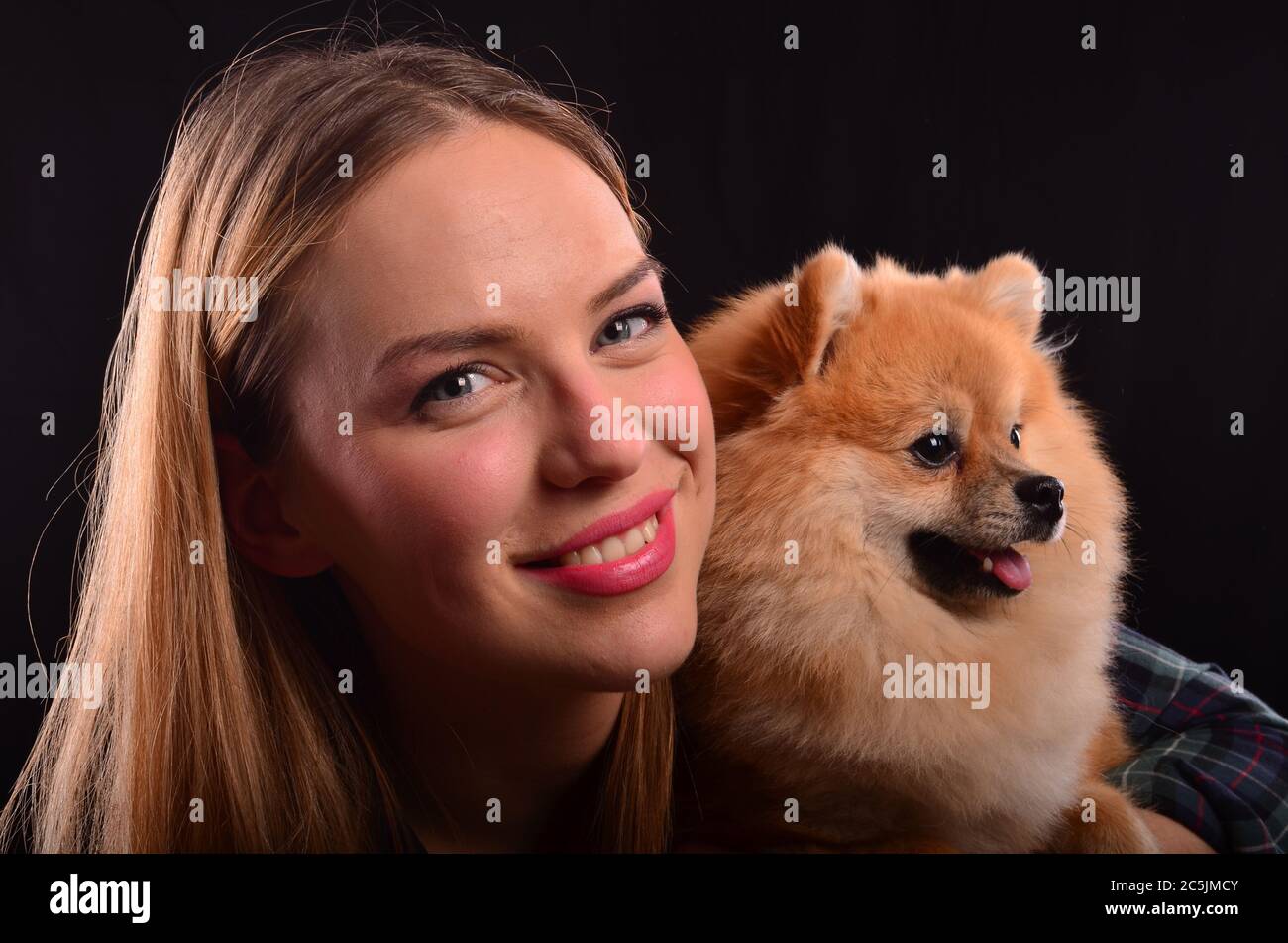 Portrait of beautiful smiling blonde girl and young Pomeranian or Spitz dog with fluffy fur Stock Photo