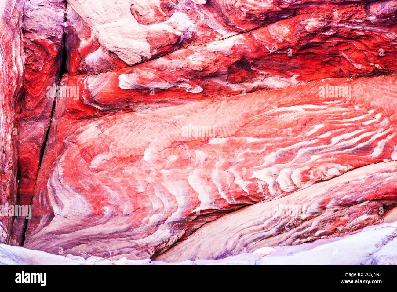 The red sandstone rock surface of the canyon known as Al Siq at the entrance to the Pink City of Petra in Jordan. Stock Photo