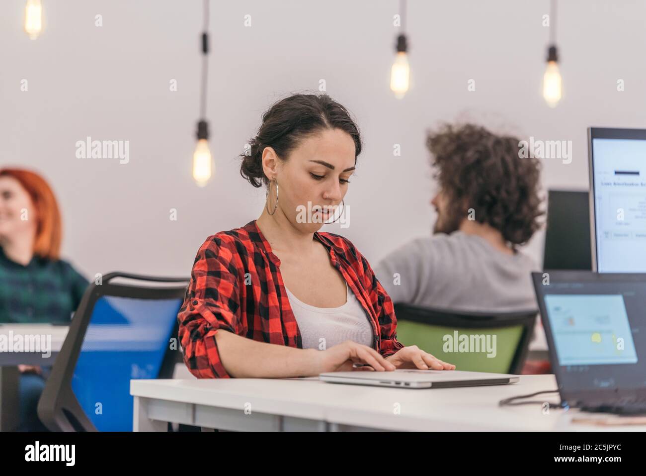 A casually dressed employee performing daily activities while working on a pc. Stock Photo