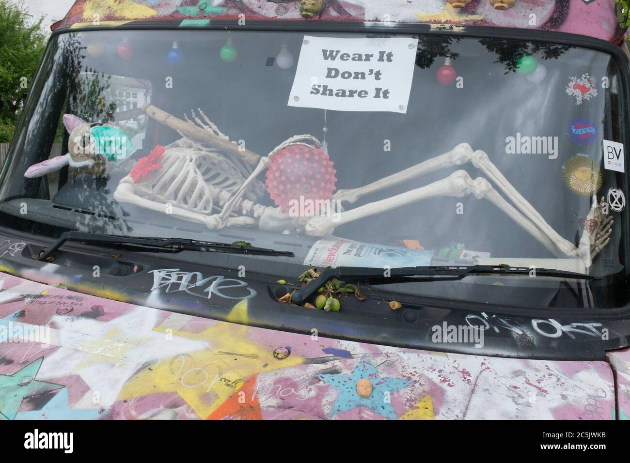 As the Coronavirus lockdown continues to ease, a further 155 UK Covid deaths are reported in the last 24 hrs, a total now of 43,730. A skeleton wearing a surgical face mask lies across the windscreen of a van in Herne Hill, on 30th June 2020, in London, England. Stock Photo