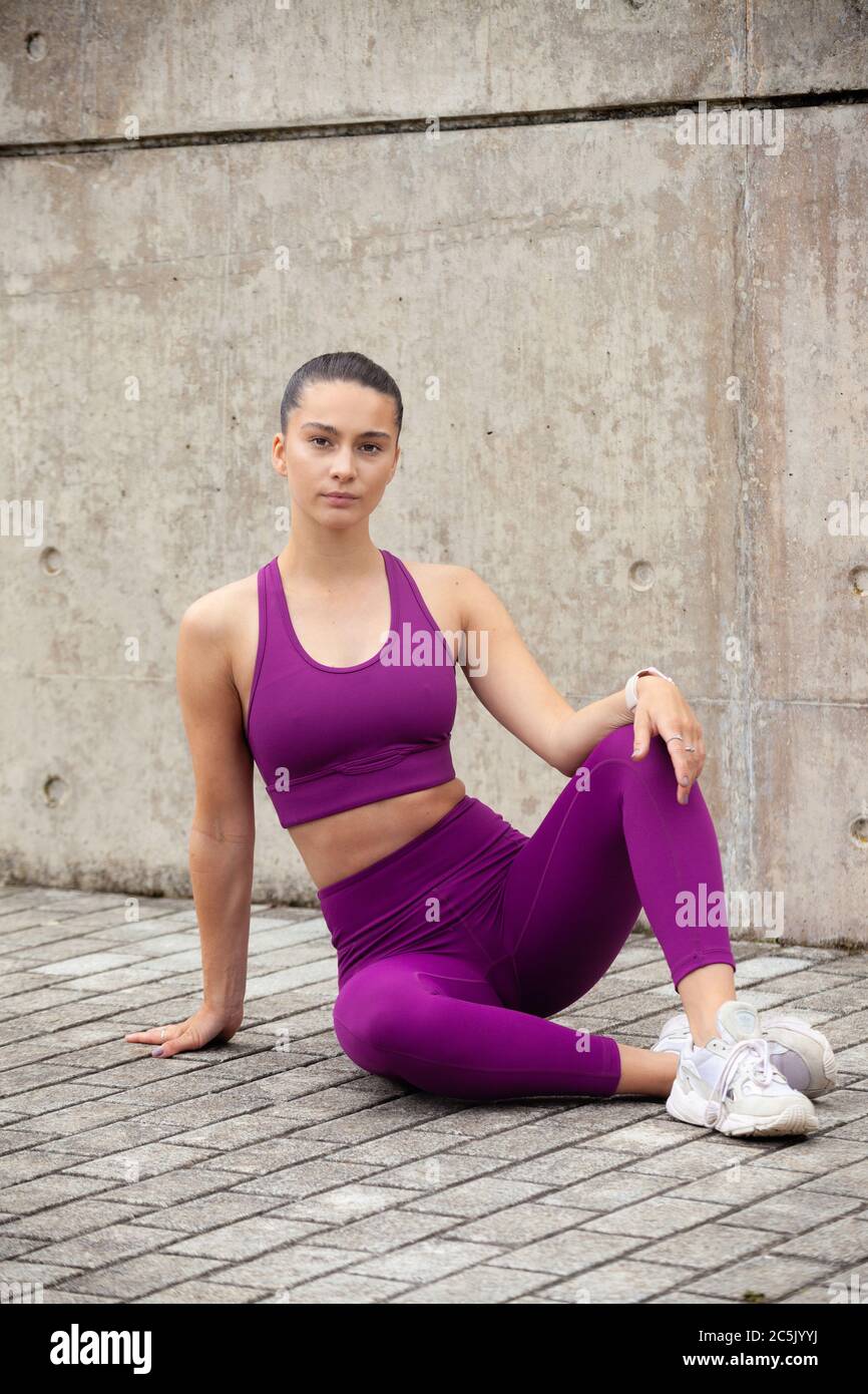 Young athletic woman wearing sportswear sitting down outside Stock Photo