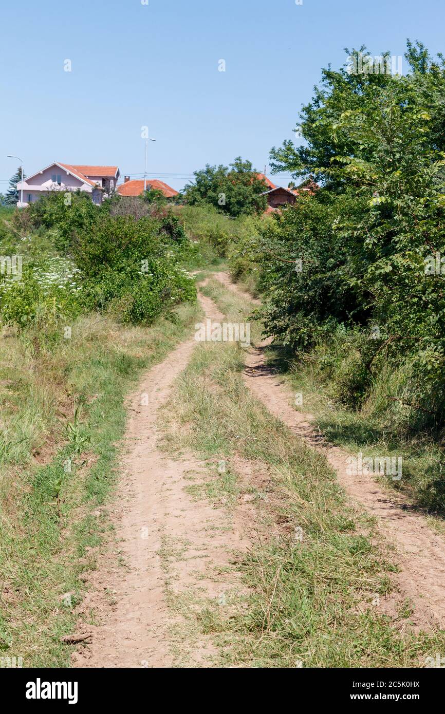 Dirt Road Near Inhabited Place With Houses in The Background Stock Photo