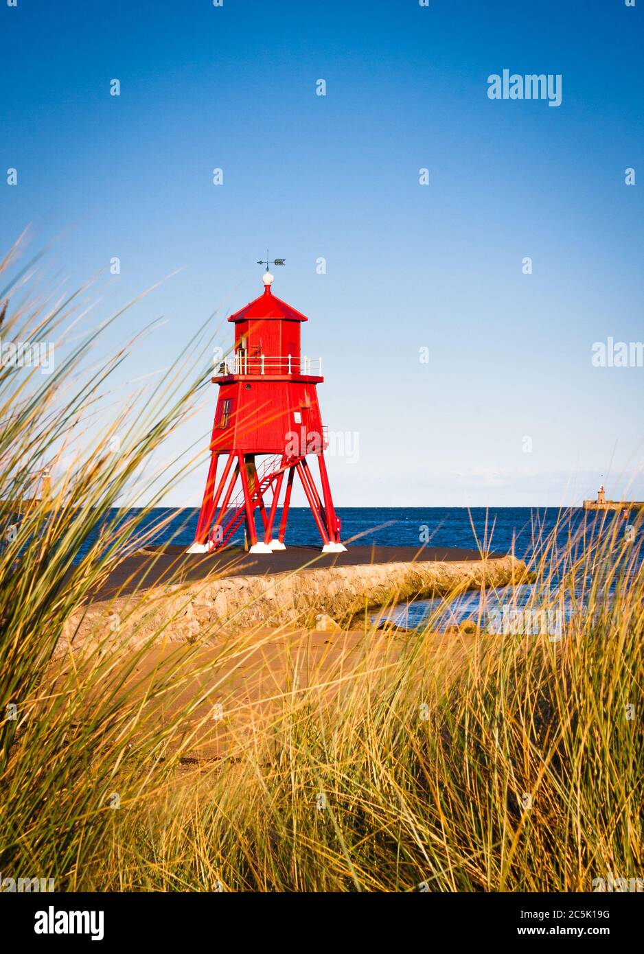 England, North East, Tyne&Wear, SouthShields, Little Haven, Pier. Lookin through the Marram grass and sand dunes towards the red lighthouse and pier i Stock Photo