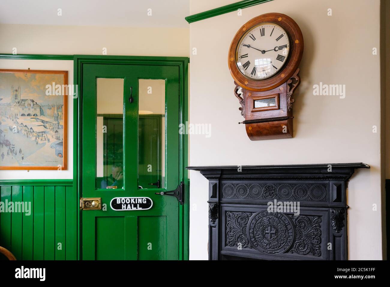 Traditional interior view of a bygone era railway waiting room. Showing a vintage wall clock and fire mantel, for passengers to wait before departure. Stock Photo