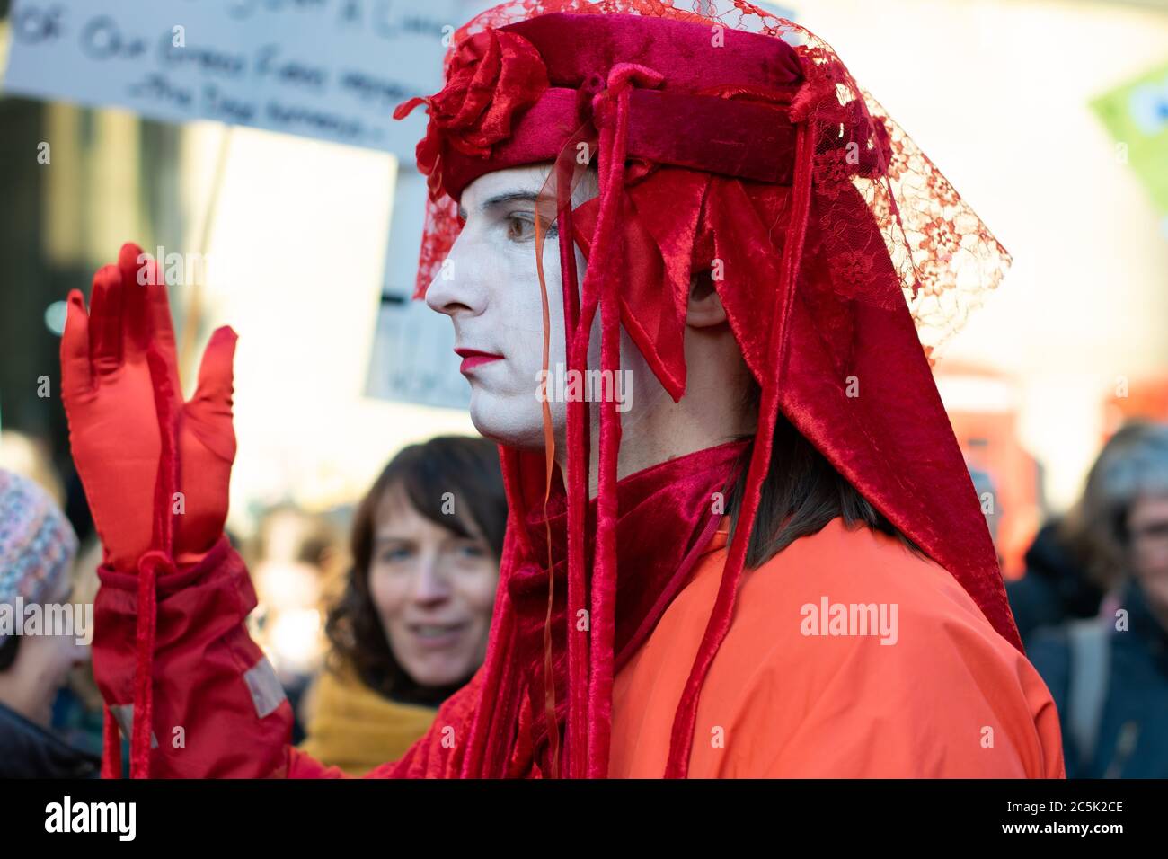 Global climate strike in St Peter's Square, Manchester UK. Extinction rebellion invisible circus red rebels. Man in profile with hand held up Stock Photo