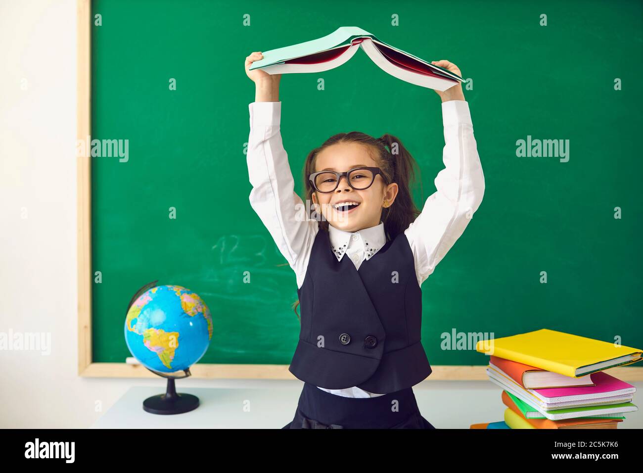 Back to school concept. Little girl with a book over her head smiling ...