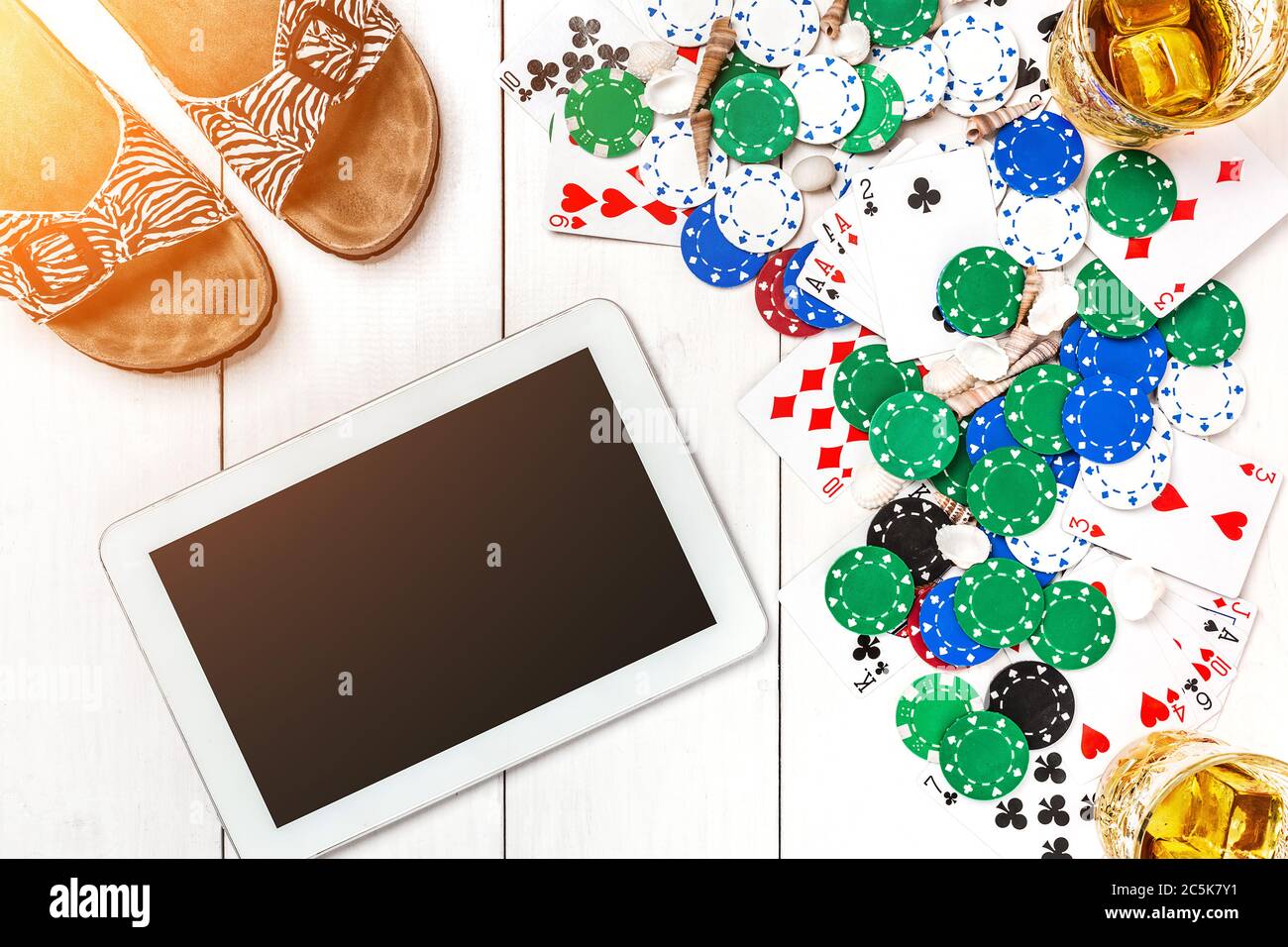 Gambling. Poker chips, cards and the dice nearby tablet on wooden table
