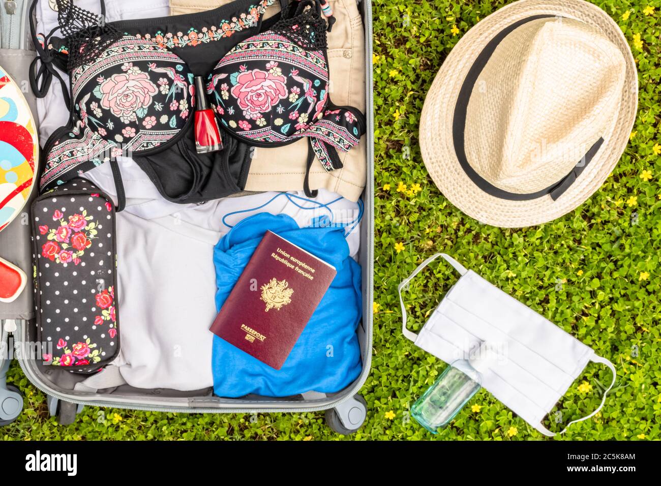 Travel wheeled suitcase with face protection mask and hydroalcoholic gel to fight the Covid-19 virus, coronavirus, allergy, epidemic and pandemic. Stock Photo