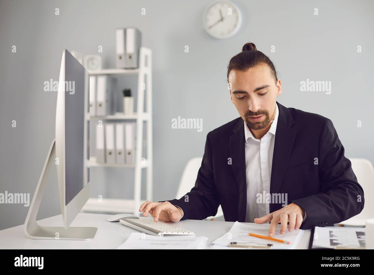 Businessman in a black jacket works. Analyzes at the computer in the office. Stock Photo