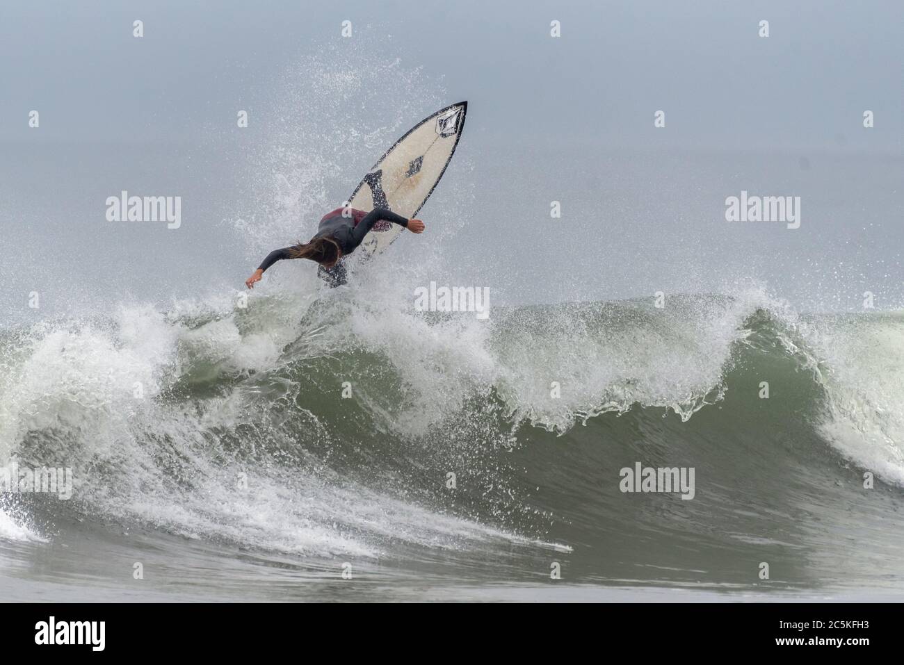 Young male surfer throws up spray and launches straight up above the face of a breaking wave at Surfer's Knoll in Ventura, California, USA on July 2, Stock Photo