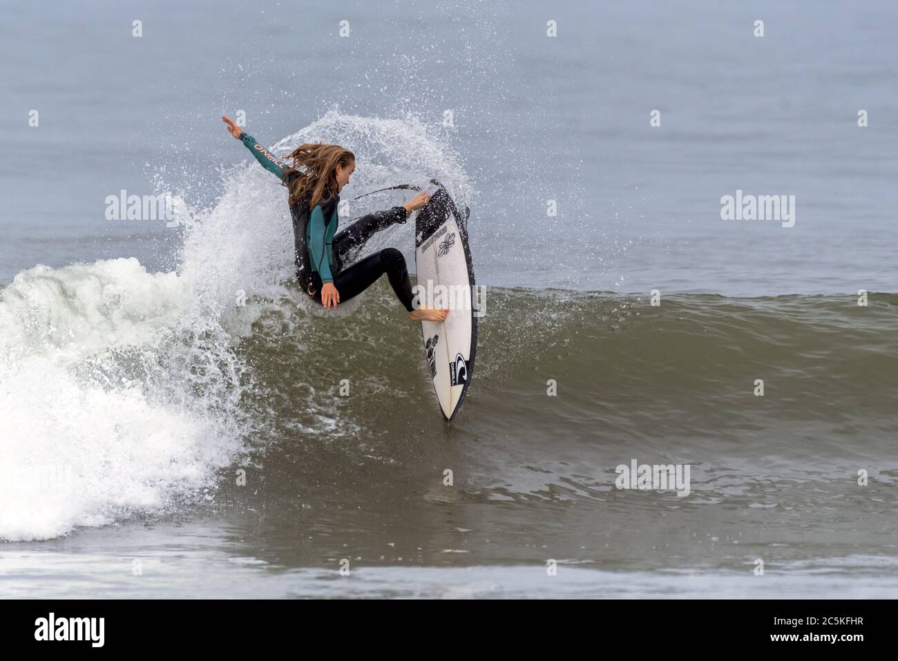 Young female teen surfer aggressively turns hard off the lip of a breaking wave and throws up spray at Surfer's Knoll in Ventura, California, USA on J Stock Photo