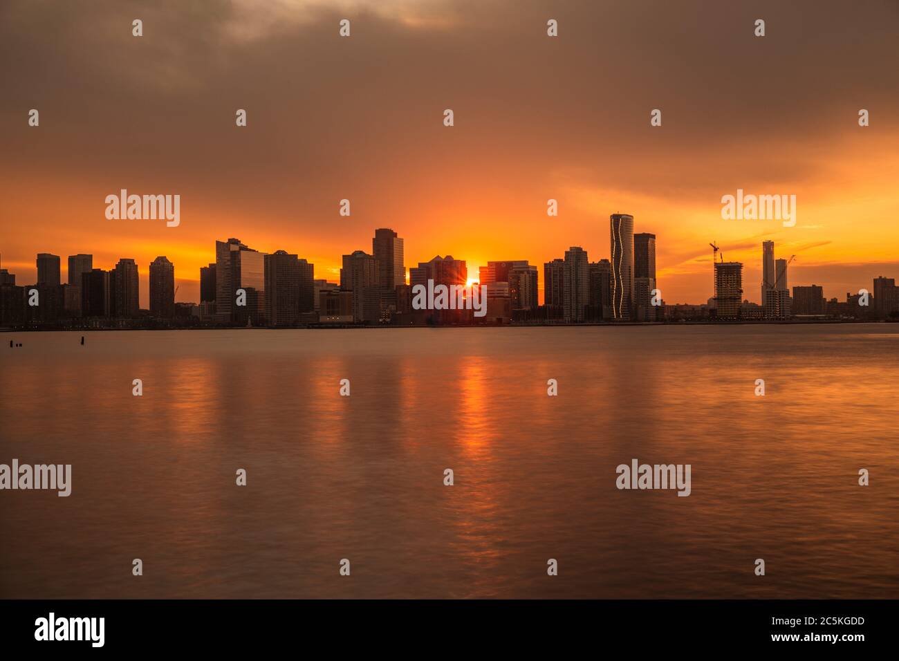 Long exposure photo at the Hudson river in New York City. Beautiful skyline. The sun is setting behind the skyscrapers. Stock Photo