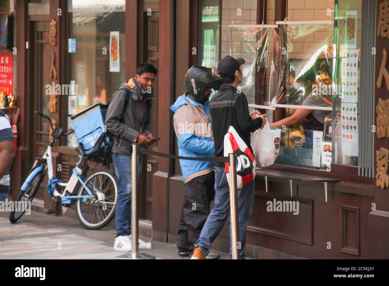 Delivery agents pick orders from a covid 19 safe take away outlet in China Town. Daily life in London on a friday ahead of the opening of pubs on the 4th of July as per new Government advice. Stock Photo