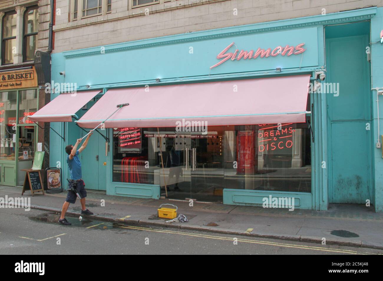 Westminster, London, UK - 3 July 2020: A worker cleans up a canopy of a pub on Wardour Street. Daily life in London on a friday ahead of the opening of pubs on the 4th of July as per new Government advice. Stock Photo