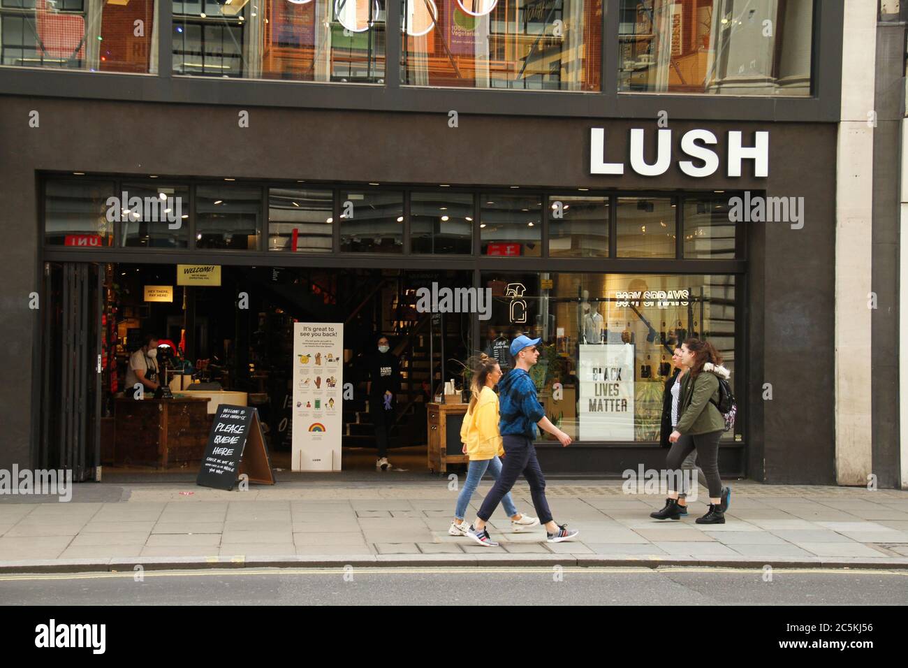 Westminster, London, UK - 3 July 2020: People walk past a shop with a Black Lives Matter placard displayed n it window on Oxford Street. Daily life in London on a friday ahead of the opening of pubs on the 4th of July as per new Government advice. Stock Photo