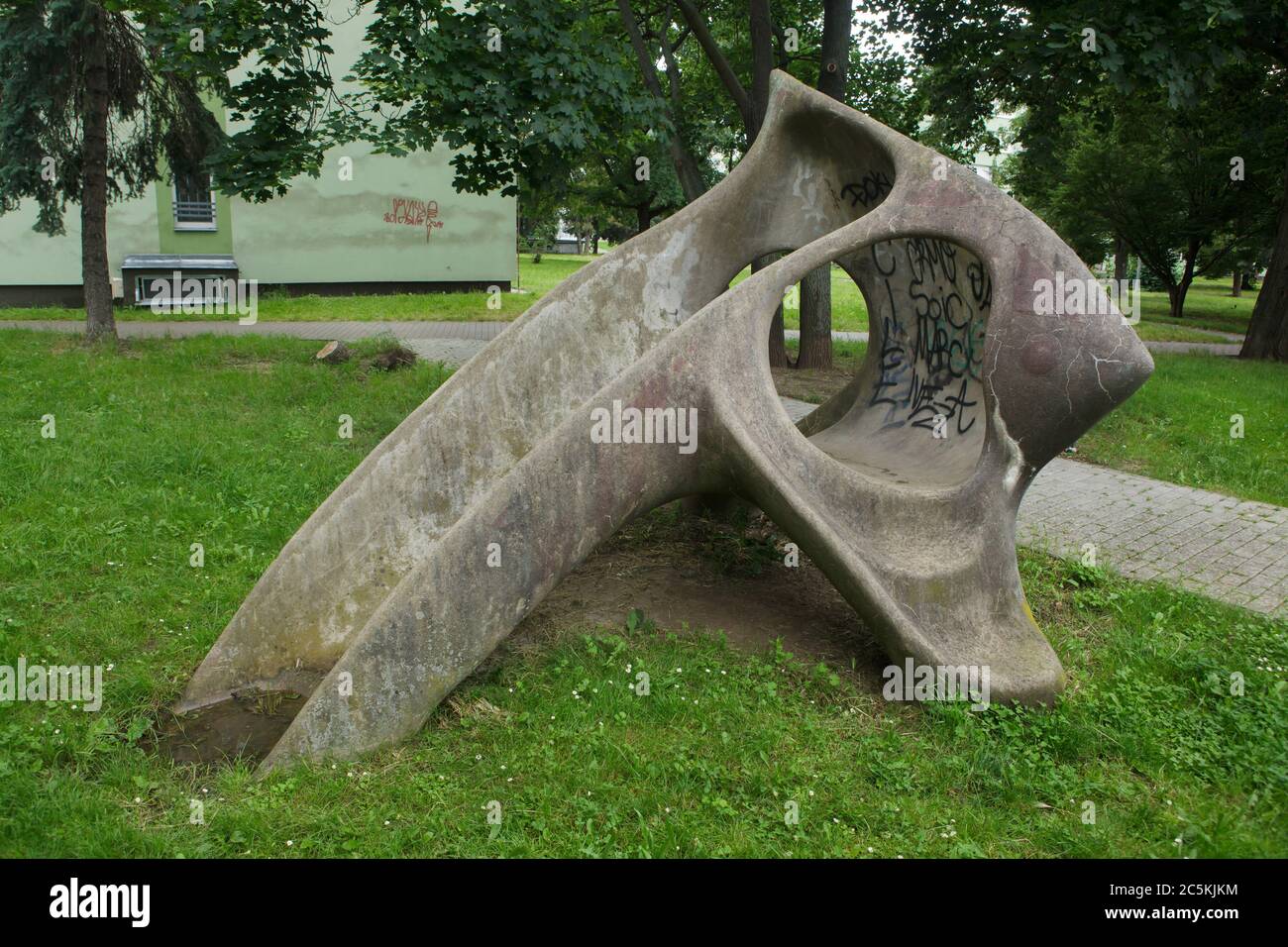 Concrete children's slide designed by Czech modernist sculptor Eleonora Haragsimová (1965) installed in the courtyard of the Invalidovna experimental housing complex in Karlín district in Prague, Czech Republic. The slide officially known as the Fish (Prolézačka Ryba) is nicknamed as the Mammoth pelvic bone by local people. In fact the children's slide is a modernist sculpture. During the communist regime in Czechoslovakia one of the few ways to install modernist artworks in public areas was to pretend the artwork is an element of a playground. Stock Photo