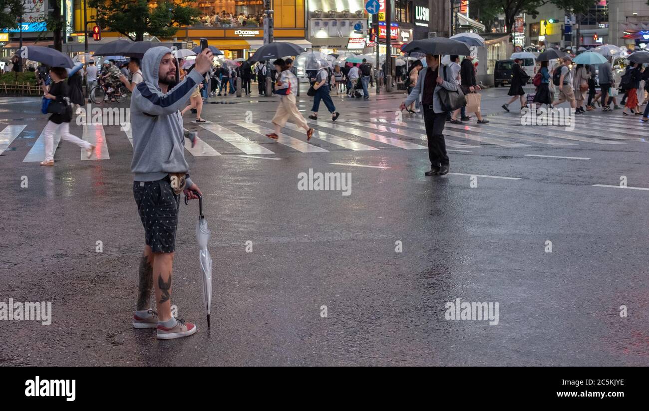 Male tourist with umbrella at Shibuya crossing, Tokyo, Japan during a ...