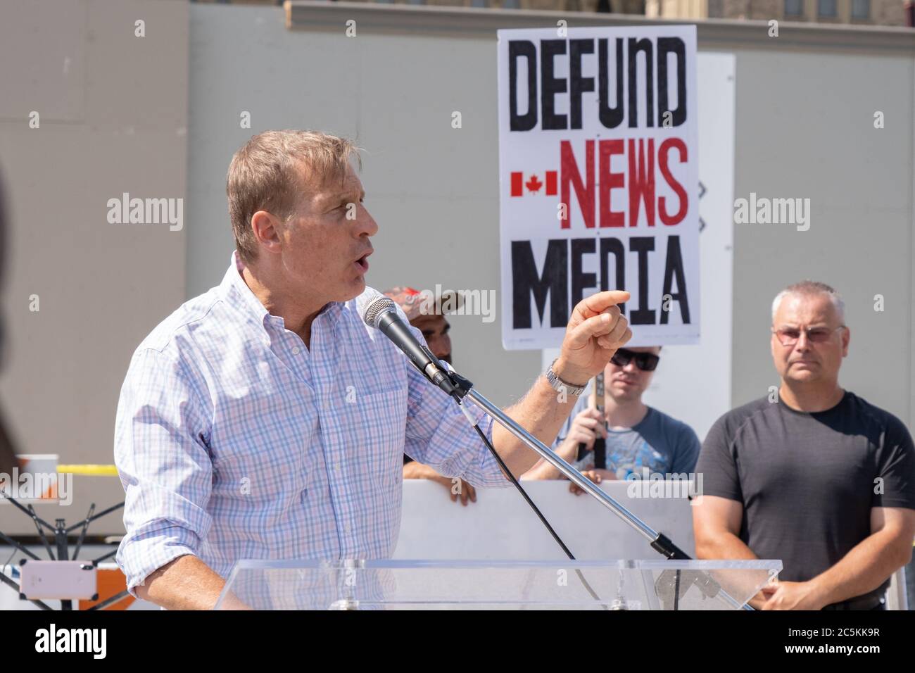 Maxime Bernier of the People's Party of Canada gives a speech at a Canada Day protest at Parliament Hill while a protestor denounces mainstream media. Stock Photo