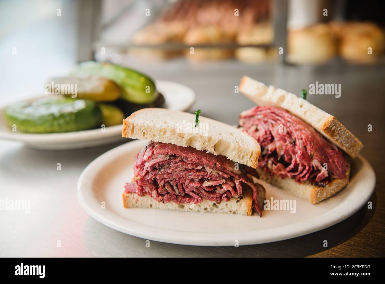 Pastrami sandwich with a side of pickles being served at a jewish deli