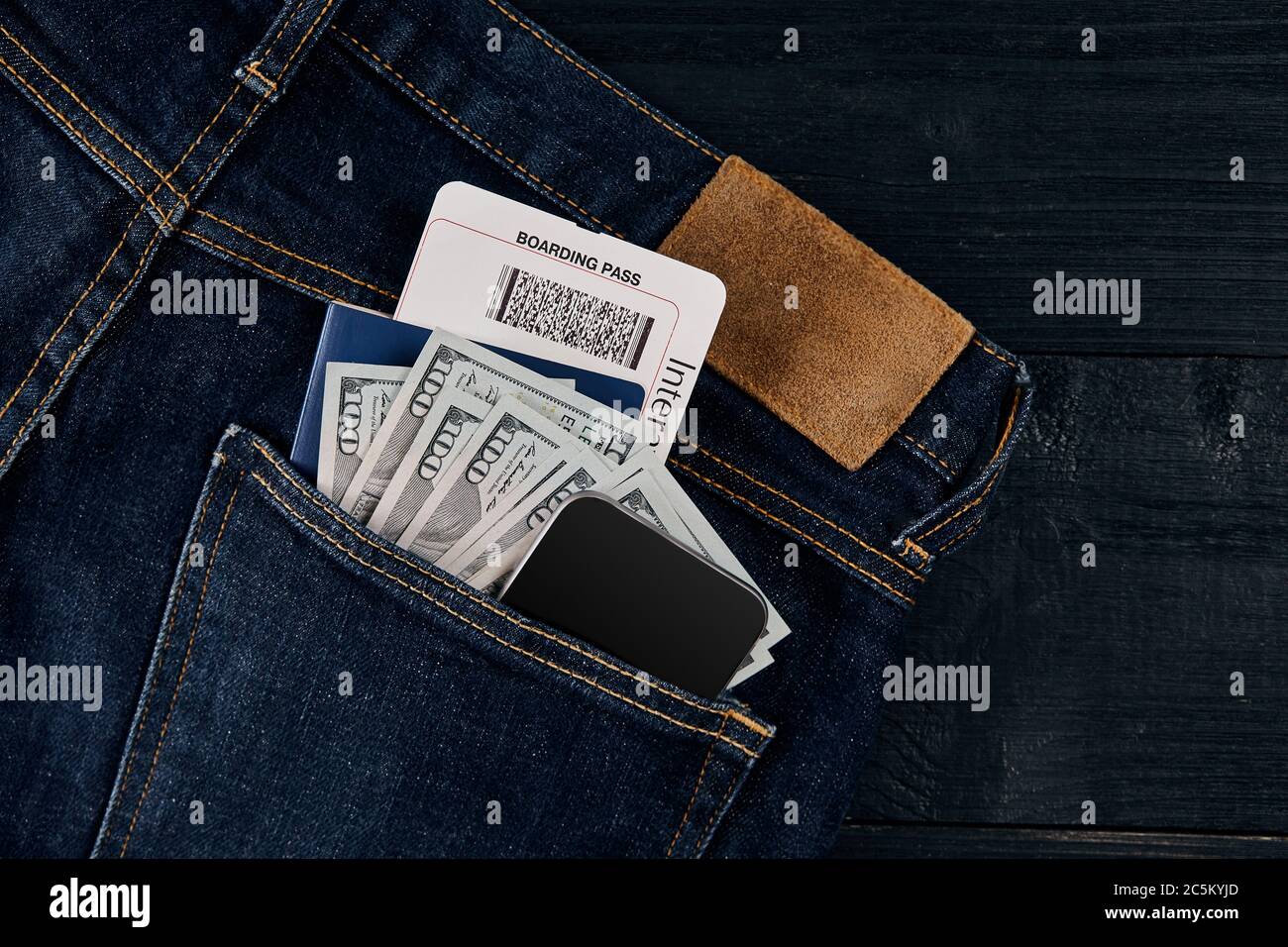 Dollars, smart, passport and plane ticket in your pocket jeans on black  wooden background Stock Photo - Alamy