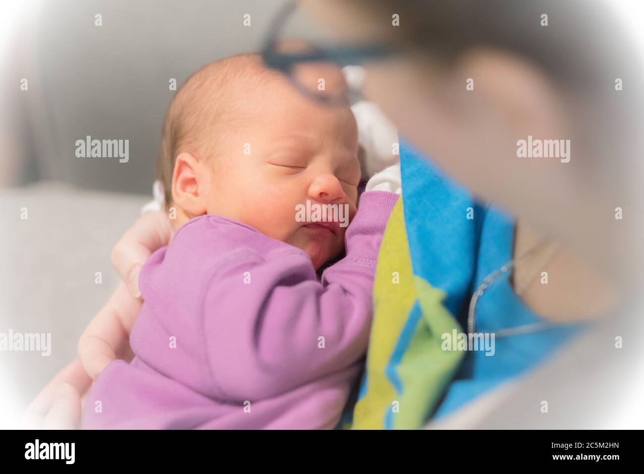 Mom holds her one month old baby girl on the shoulder while she is sleeping. Stock Photo