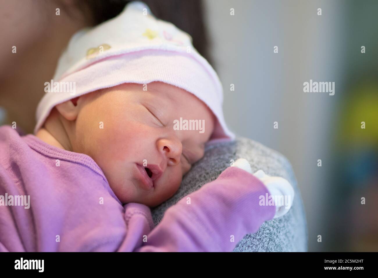 Mom holds her one month old baby girl on the shoulder while she is sleeping. Stock Photo