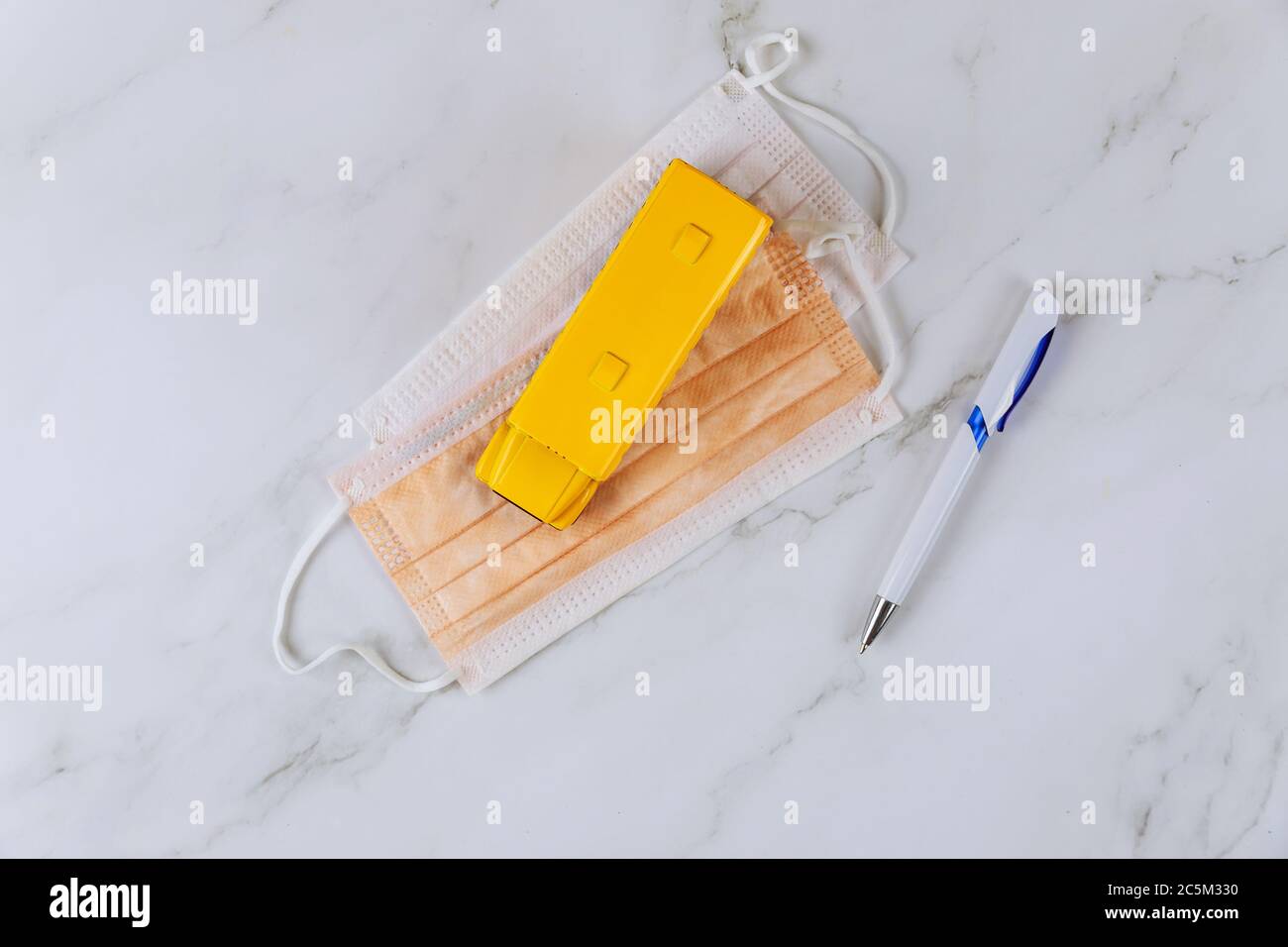 Protective face masks, pen and toy school bus. Safety rules in school