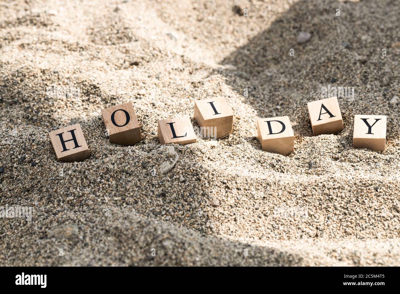 Holiday concept from wooden cubes. Wooden cubes embedded in sand Stock ...