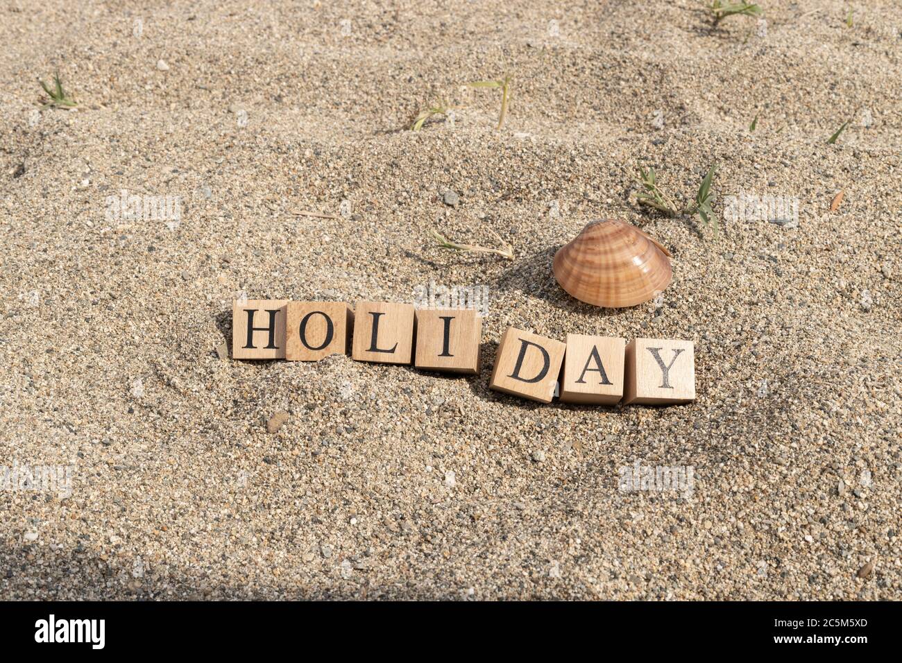 Holiday concept from wooden cubes. Wooden cubes embedded in sand Stock ...