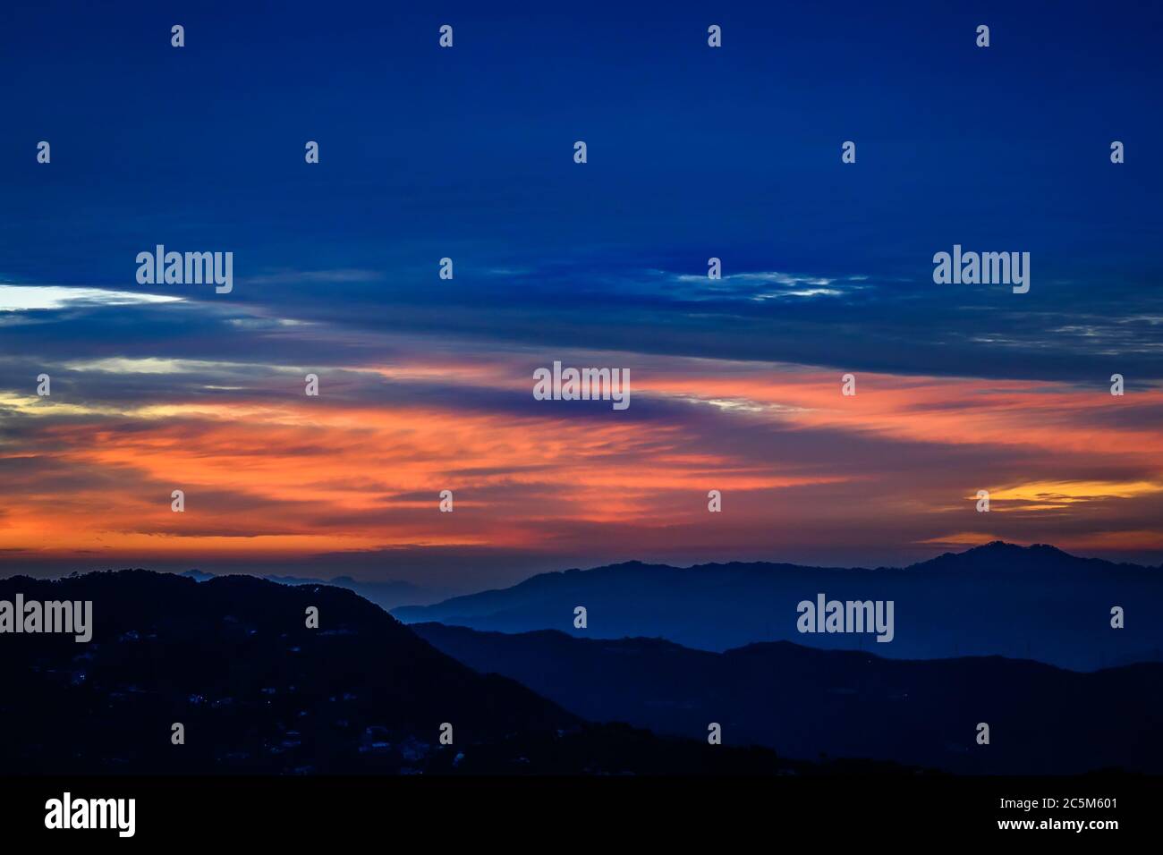 Colorful, vibrant, burning sunset skies, dramatic clouds, and silhouette of Himalayan mountains in winter Trek to Dalhousie, Himachal Pradesh. Stock Photo