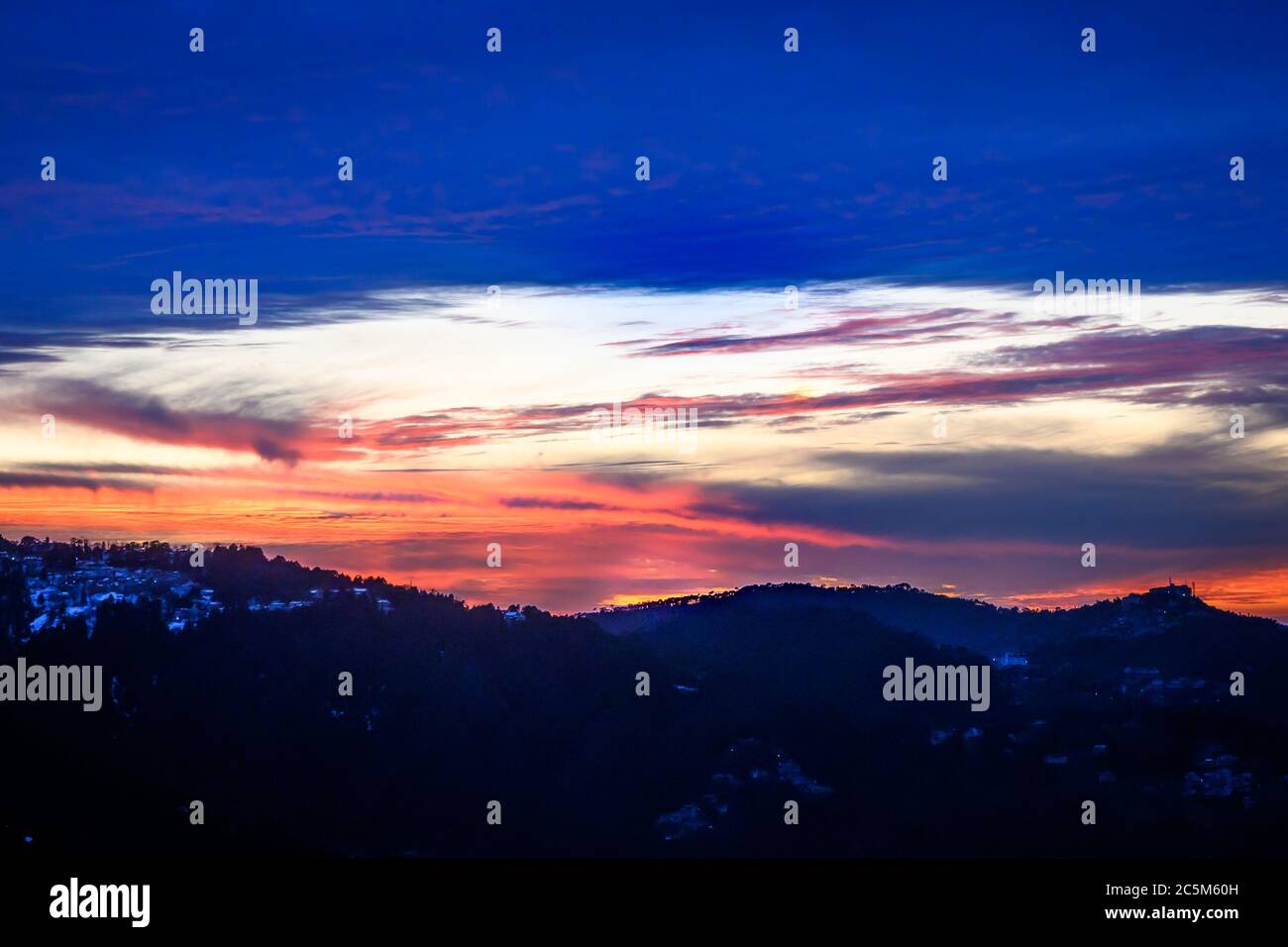 Colorful, vibrant, burning sunset skies, dramatic clouds, and silhouette of Himalayan mountains in winter Trek to Dalhousie, Himachal Pradesh. Stock Photo