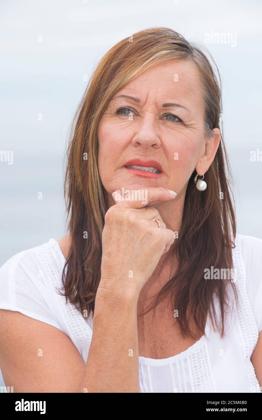 Portrait attractive mature woman looking concerned and worried, thoughtful with hand on chin. Stock Photo