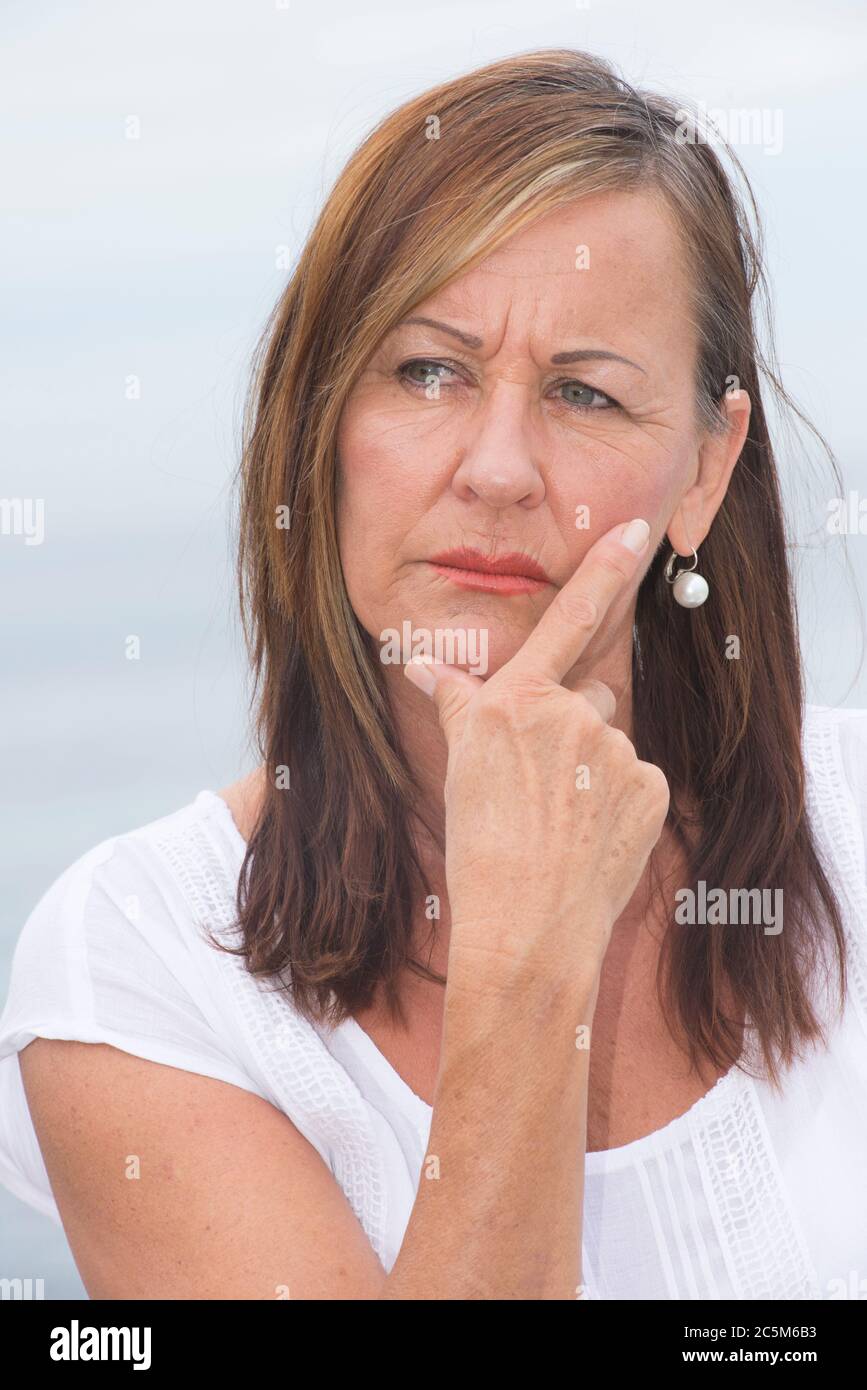 Portrait attractive mature woman looking concerned and worried, thoughtful with hand on cheek. Stock Photo