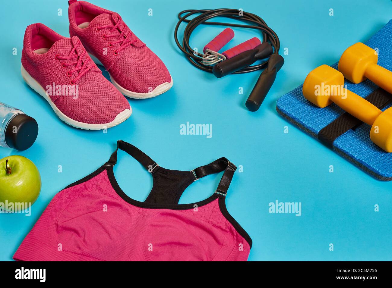 Flat lay of dumbbell, bottle of water, jump rope and sneaker, sport equipments, fitness items
