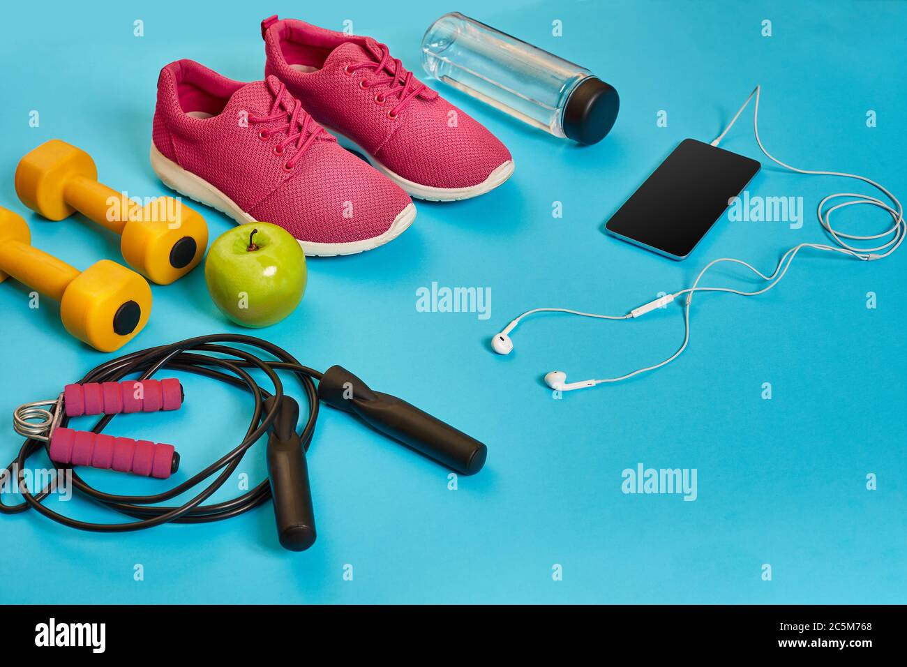 Flat lay of dumbbell, bottle of water, jump rope and sneaker, sport equipments, fitness items