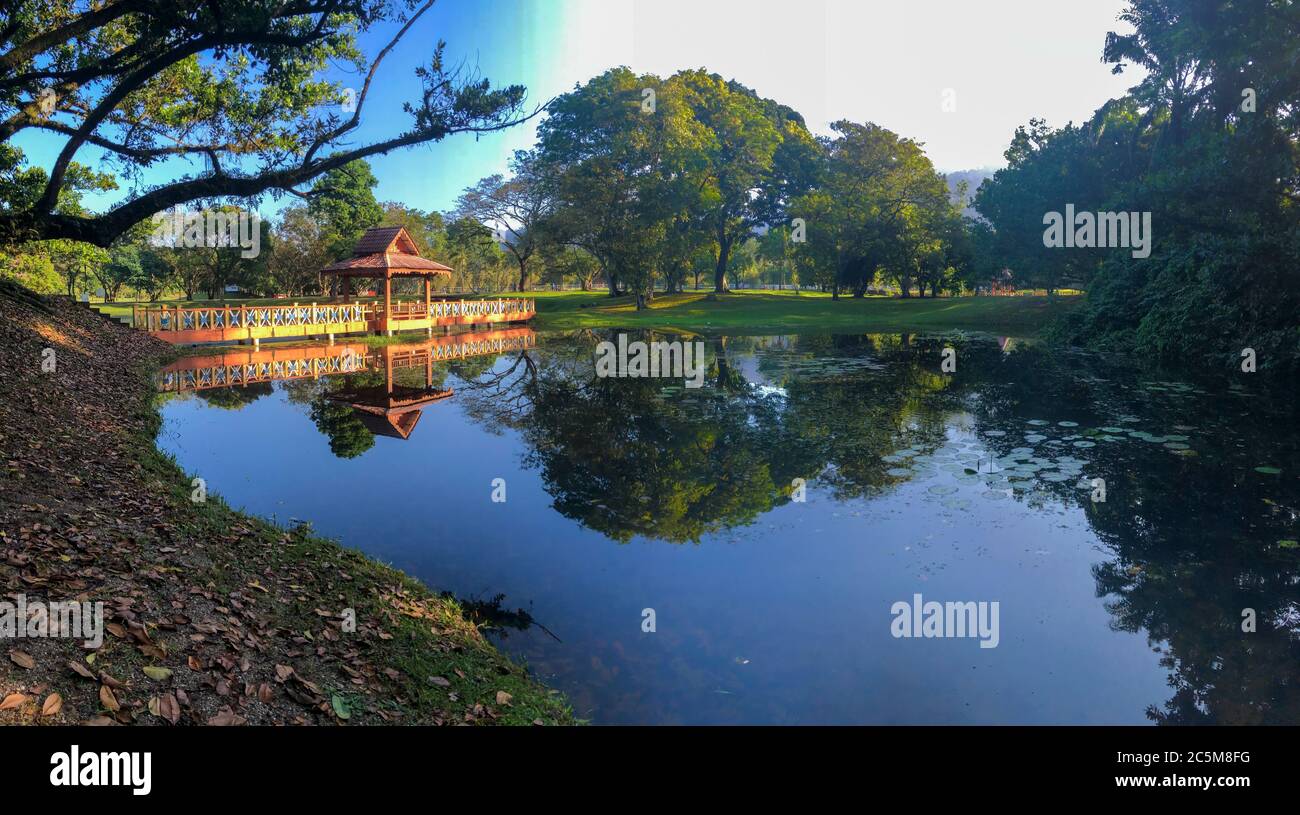 Footbridge over a lake, blue sky, trees and reflections in the water Stock Photo