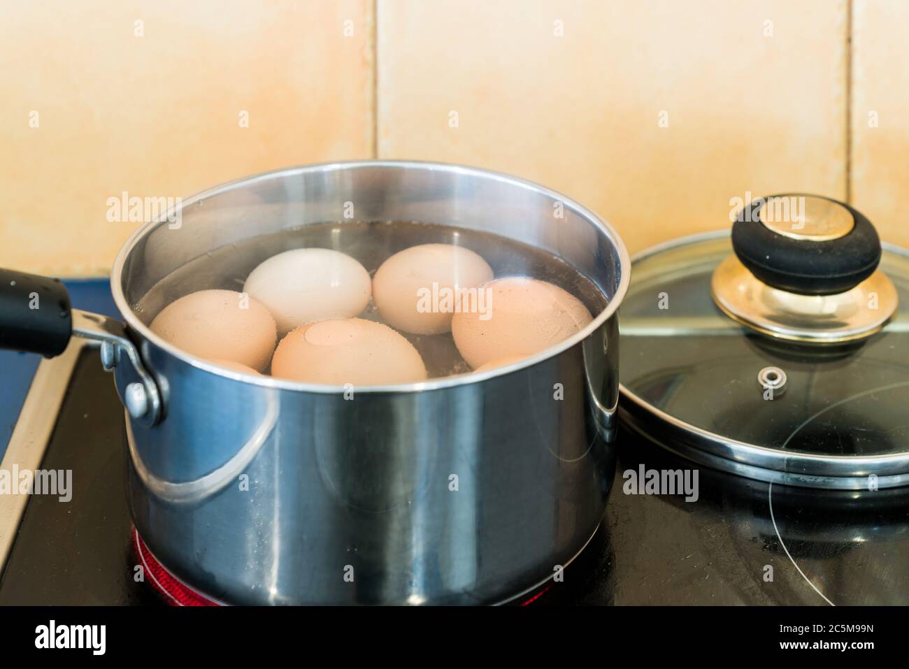 Eggs boiling in stainless steel saucepan on cook top in home kitchen Stock Photo