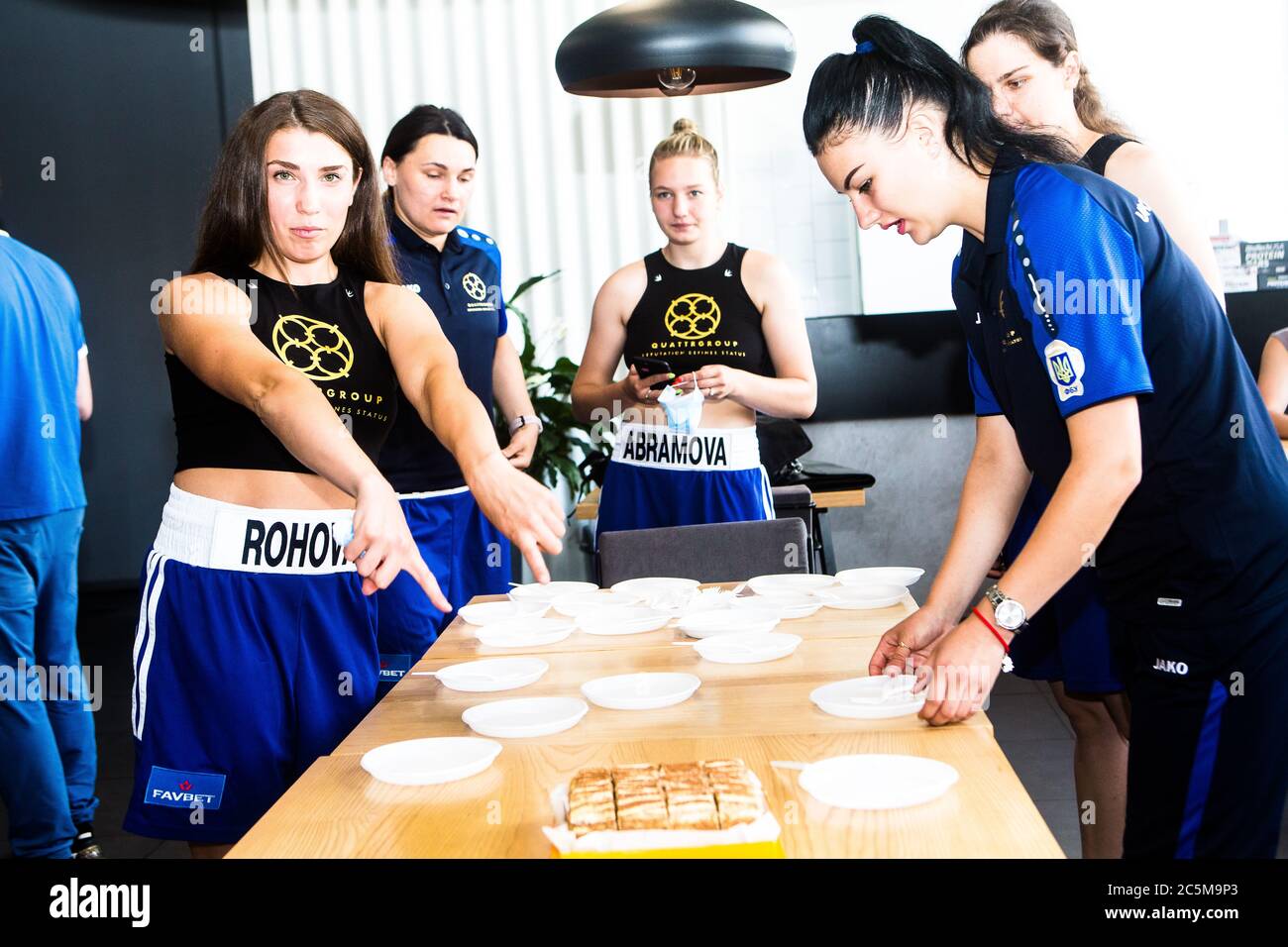 Ukrainian girls boxers incl Katya Rogova,left, and friends in Ukrainian Women's boxing League ready enjoy sweet cake w/drink after weigh in on scales. Stock Photo