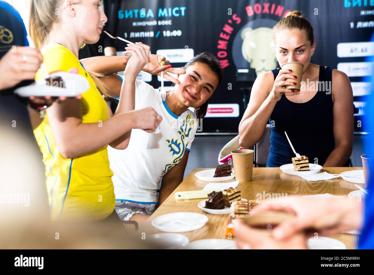 Ukrainian girls boxers Lera Eroshenko (white T-shirt) and friends in Ukrainian Female boxing League enjoy sweet cake w/drink after weigh in on scales. Stock Photo