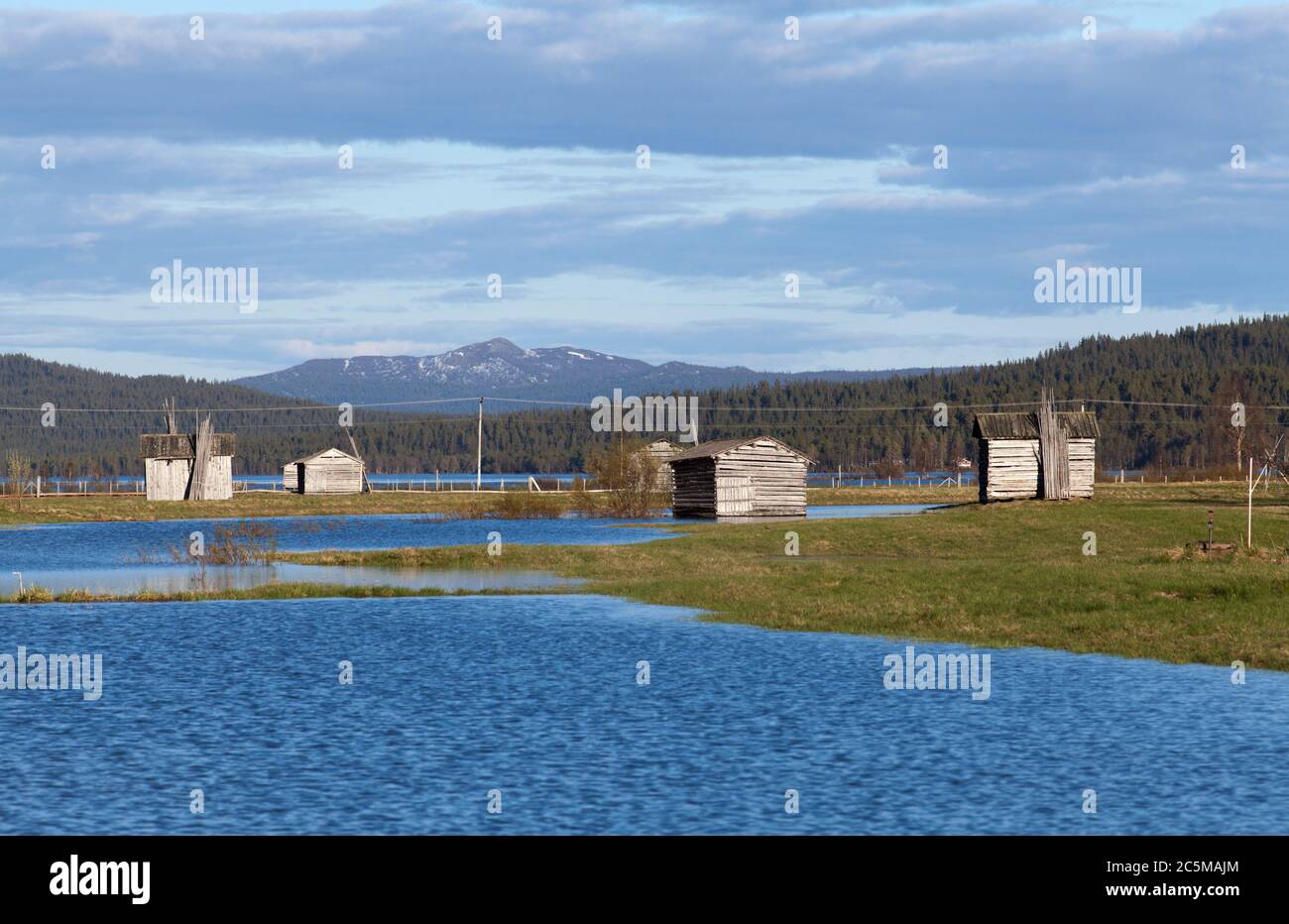 Water from a flooded river cover a delta land. Wooden barns on the